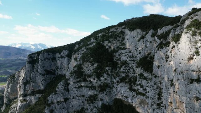 Aerial drone footage over Frasassi Gorge, Italy: rocky cliffs, green vegetation and dramatic natural landscape. Ideal for travel, nature and geological projects.