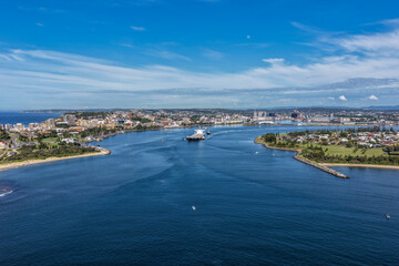 Fototapeta premium Aerial drone view of a large cargo ship being escorted by tug boats through Newcastle Harbour in New South Wales, Australia.