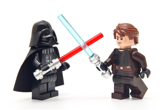 Lego minifigure of Darth Vader from Star Wars with red lightning sword against an Anakin with blue sword isolated on white. Editorial illustrative image of popular plastic constructor.