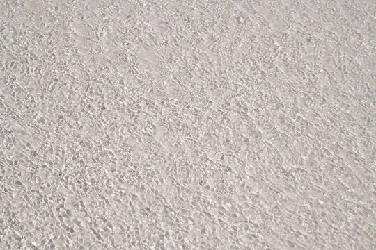 Transparent water in clear sea for clean purity. Transparent water on beach sand for texture background. Transparent water in shoreline ripples for serene pattern. Transparent water on coastal surf