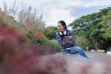 Young Asian woman enjoying reading in park