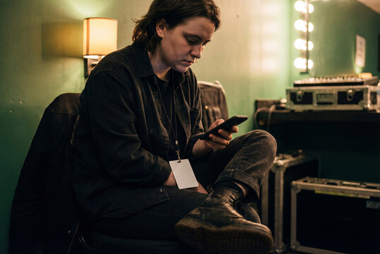 Young adult with backstage pass using phone in dressing room