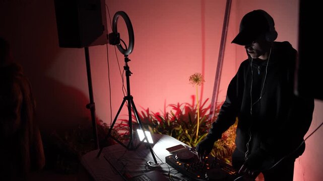 Music producer mixing electronic tracks with red ambient lighting in home studio