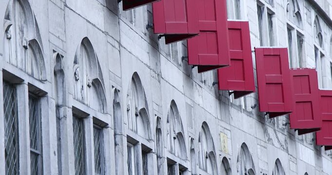 Row of red shutters opening on a historic building facade in The Netherlands.