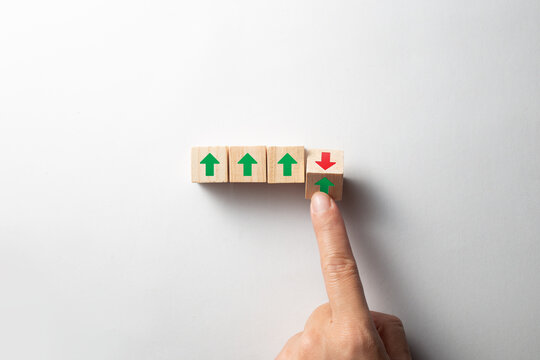 Hand flipping wooden block from green up arrow to red down arrow. 