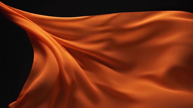 A vibrant orange fabric flows gracefully through the air against a dark background