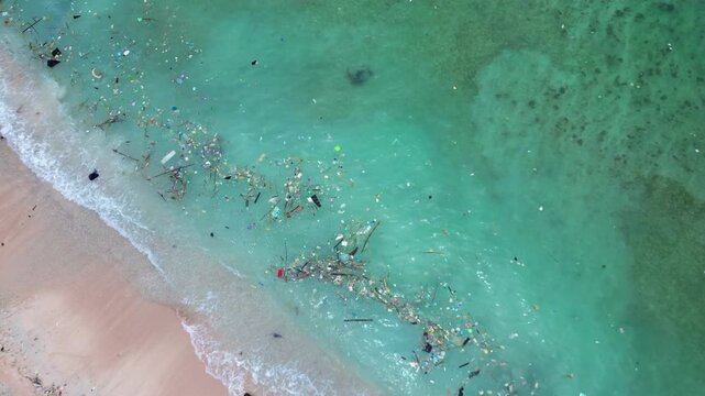Ocean water showing a sea turtle swimming near the shore and accumulating plastic waste, highlighting environmental pollution impact. Perfect aerial view drone camera pointing down