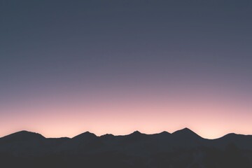 Obraz premium A serene mountain landscape at sunset with a vibrant sky