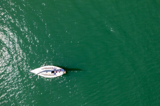 Aerial view of sailboat on calm emerald sea, minimalist drone shot of white yacht in open water, travel freedom and summer adventure concept, ocean exploration and maritime lifestyle background