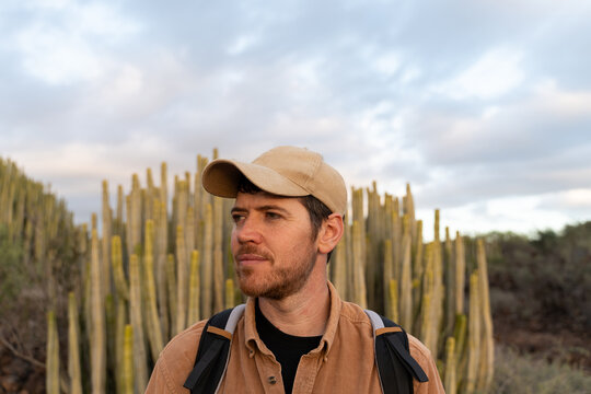 Portrait of traveler with backpack at sunset in desert with cactus
