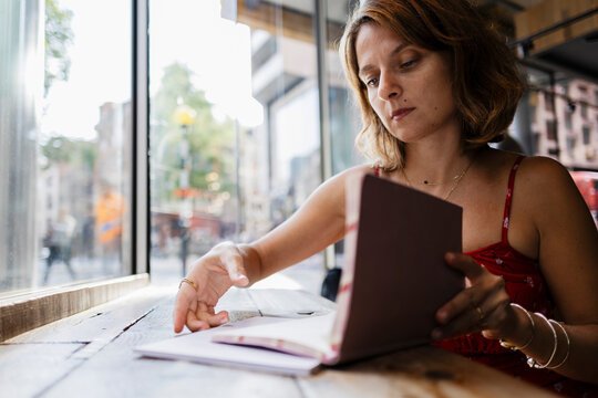 Woman reading a book in a relaxed urban cafe setting by window