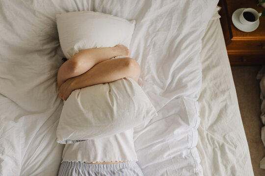 Fatigued woman hugging pillow in bed during a stressful morning