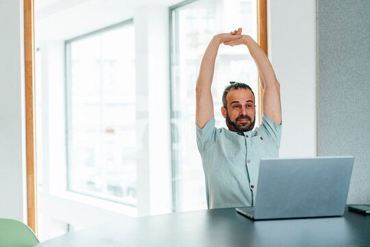 Developer stretching at desk during work in modern office