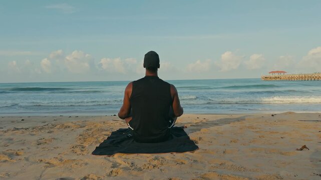 Back view of a man meditating in upward salute yoga pose on a tropical beach with calm waves and blue skies, capturing mindfulness, peace, and coastal serenity.
