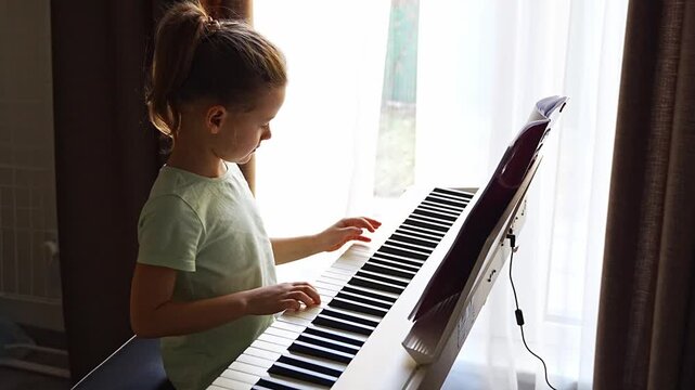 Little girl sitting at piano and playing music at home, expression and careful posture. Childhood music education, creative development, concentration, discipline, and calm learning atmosphere