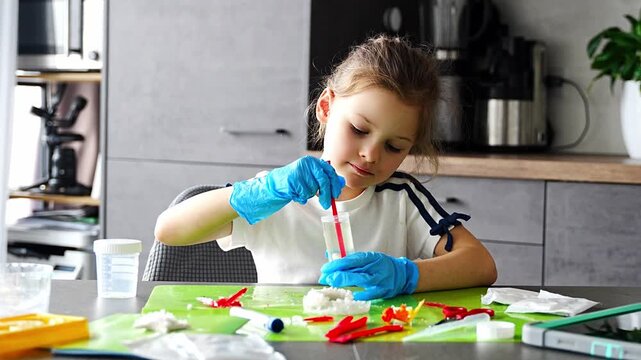 Young girl stirring chemical solution with measuring spoon in cup during crystal growing experiment at home. Chemistry practice and early STEM education through practical laboratory activity.