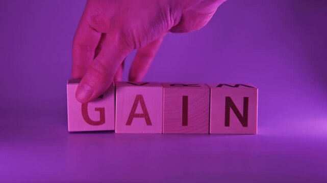 Blocks with letters are arranged in a sequence showcasing the transformation from pain to gain. A hand moves the blocks to illustrate the concept of change and growth in a clear and simple manner