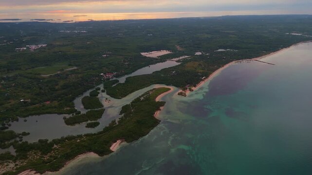 Aerial vista of the tropical shores of Bantayan Island, Philippines. This drone shot captures the meeting of lush vegetation and the quiet sea under a soft evening horizon