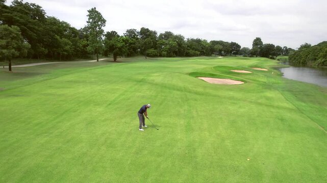 Drone view of professional male golfer playing on scenic golf course. 
