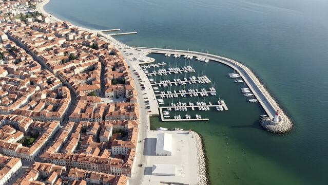 Aerial view of a coastal city with a marina and boats docked in the harbor near buildings