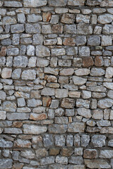 Fototapeta premium Old stone wall with irregular rough texture and weathered appearance