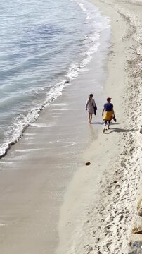 Paseo por arena de playa paradis&iacute;aca en verano de pareja y brisa marina en orilla con huellas descalzos