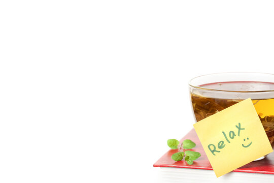 Book with a glass cup of herbal tea on top of it and yellow sticker note Relax isolated white background space for text copy space macro