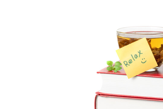 Stack of books with yellow sticker note Relax and a glass cup of herbal tea front view isolated white background space for text copy space macro