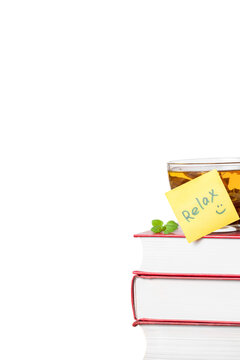 Stack of books with yellow sticker note Relax and a glass cup of herbal tea front view isolated white background space for text copy space vertical macro