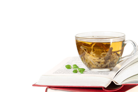 Stack of books and one opened book on top with a glass cup of herbal tea front view isolated white background space for text copy space macro