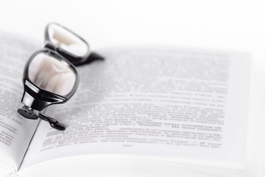 One opened book pages with glasses on top front view isolated white background macro