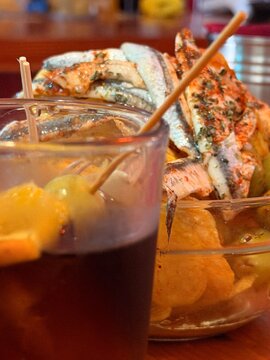 Marinated anchovies with herbs and a skewer with olive, representing spanish tapas