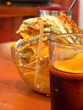 Fresh anchovies, boquerones en vinagre, served as a spanish appetizer with an orange garnished beverage