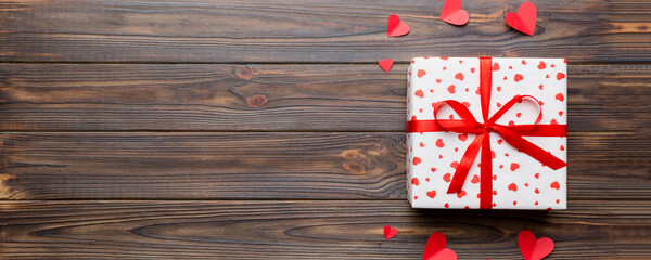 Fototapeta premium Valentine day composition: red gift box with bow and heart. Christmas present. View from above. Space for text. Holday greeting card
