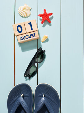 Flip-flops, sunglasses and seashells resting on light blue wooden background celebrating august 1st