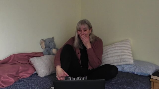 Mature woman finishing video call and waving goodbye on laptop at home