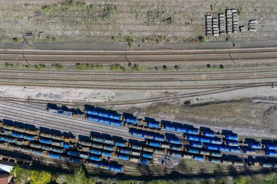 Top down aerial of rail yard in York in the UK with stacked sleepers multiple tracks and freight wagons arranged across an industrial landscape in early spring with strong linear patterns