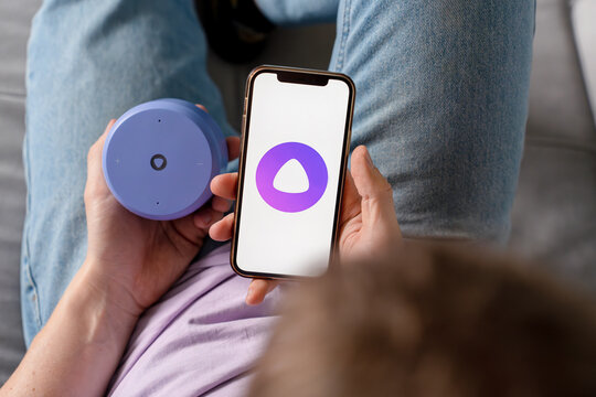 A man holds a smartphone with the Yandex Alice AI app and adjusts the Alice speaker. Saint Petersburg, Russia - 7 Apr 2026