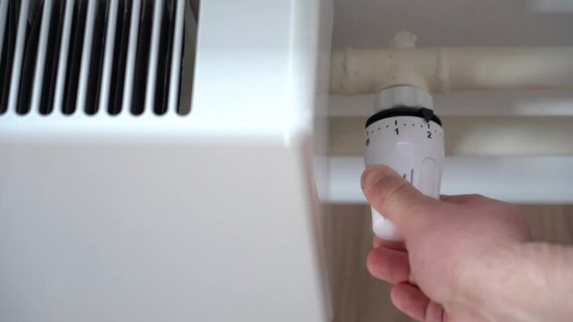 Radiator temperature dial. heating in a private house. The man adds heat to the radiator. Cold weather. Heat in the house with heating. High quality FullHD footage