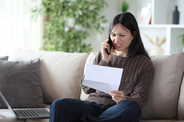 Angry asian woman claiming on phone at home