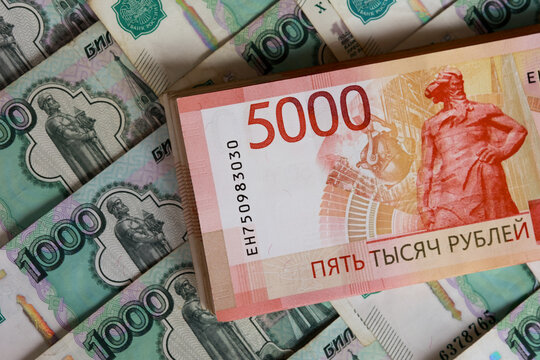 Thick stack of 5000 ruble bills on scattered 1000 ruble notes