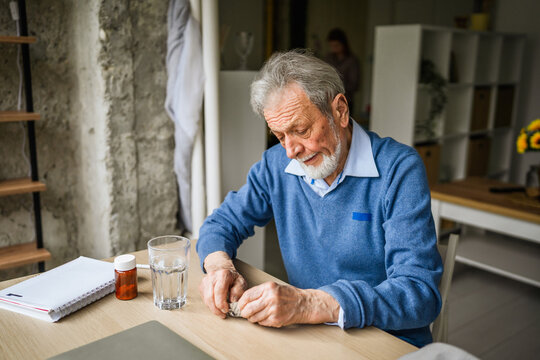 Senior man taking daily medication pills at home