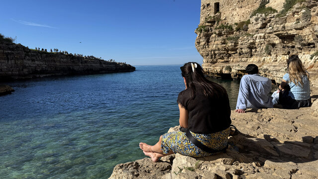 People relaxing on cliffs in Polignano a Mare Puglia overlooking Adriatic Sea, Italy