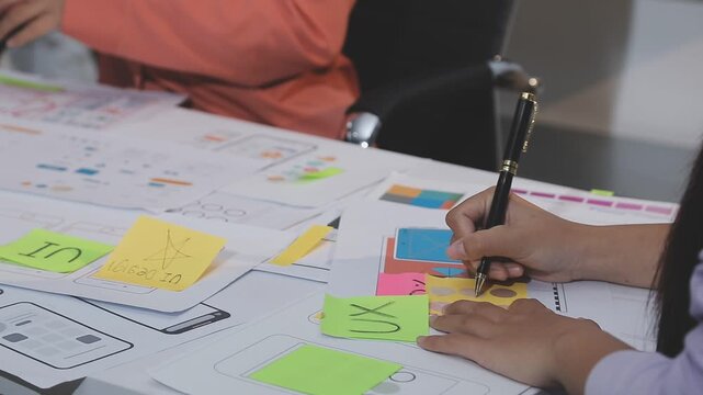 Asian uxui designer working on website design using sticky notes and wireframes