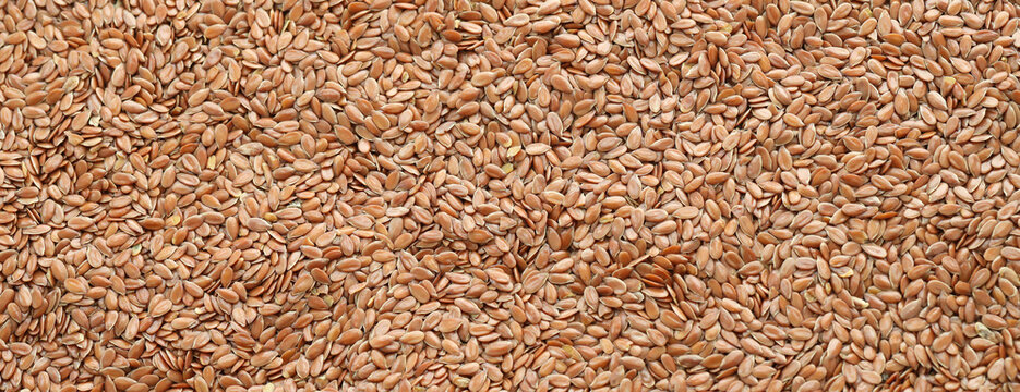 Brown flax seeds in big pile on table close up. Large amount of flax seeds