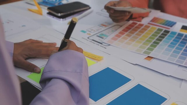 Asian uxui designer working on website design using sticky notes and wireframes