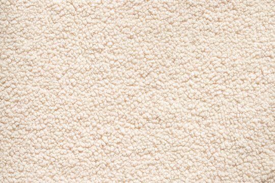 Top view of soft beige sherpa fleece texture with fluffy faux sheepskin surface and curly woolly material for cozy winter clothing background