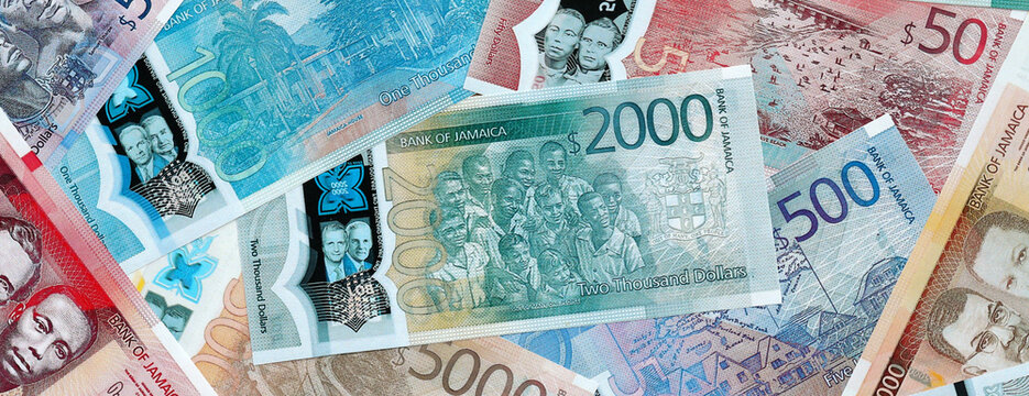 Jamaican dollar money banknotes pile on table. Jamaica bills of JMD currency close up