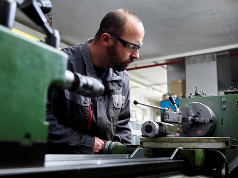 Metal construction technician working at a lathe in his workshop