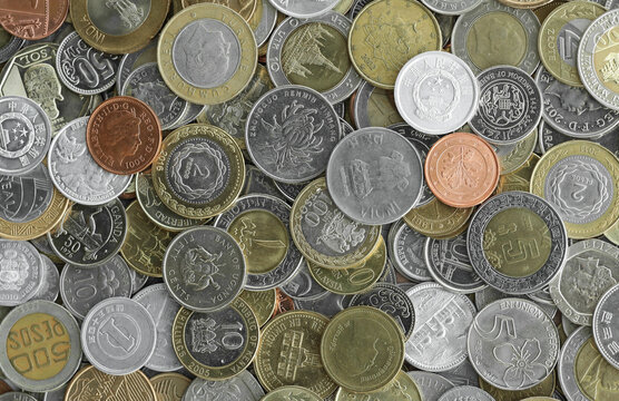 Pile of global currencies, various coin types visible up close. Different nations money together